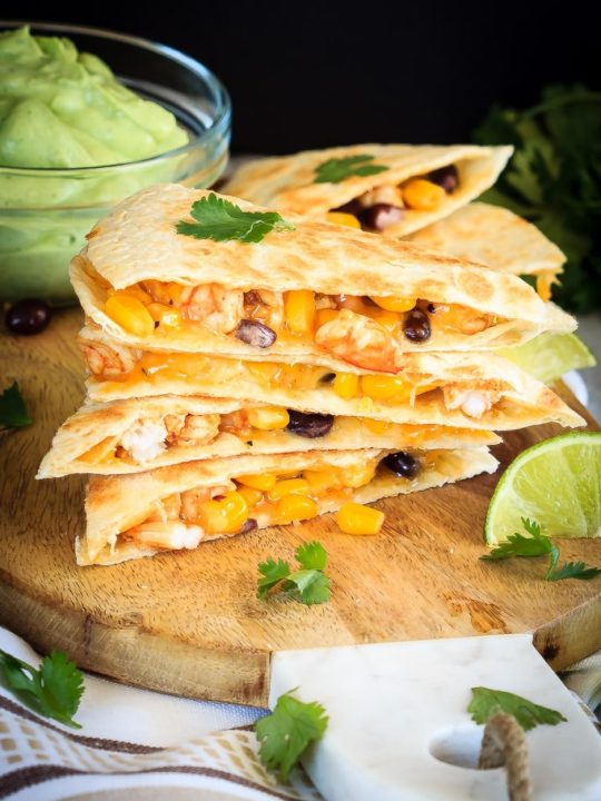 Shrimp quesadillas filled with corn, black beans and cheese, and an avocado cilantro lime cream dipping sauce. Quick and easy and everyone loves them!