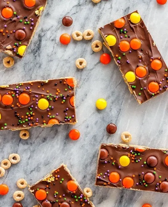 These crunchy chocolate peanut butter granola bars use cereal and oats for an easy, no bake treat - with yellow and orange candy for a fun Halloween snack!