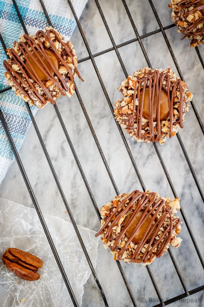 These turtle thumbprint cookies are amazing! Rich chocolate cookies rolled in chopped pecans, topped with salted caramel sauce and drizzled in chocolate!