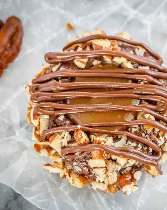 These turtle thumbprint cookies are amazing! Rich chocolate cookies rolled in chopped pecans, topped with salted caramel sauce and drizzled in chocolate!
