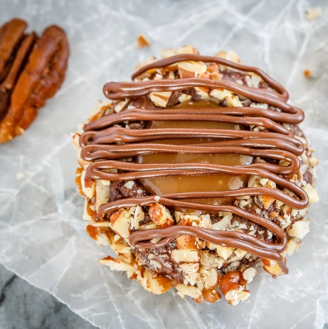 These turtle thumbprint cookies are amazing! Rich chocolate cookies rolled in chopped pecans, topped with salted caramel sauce and drizzled in chocolate!