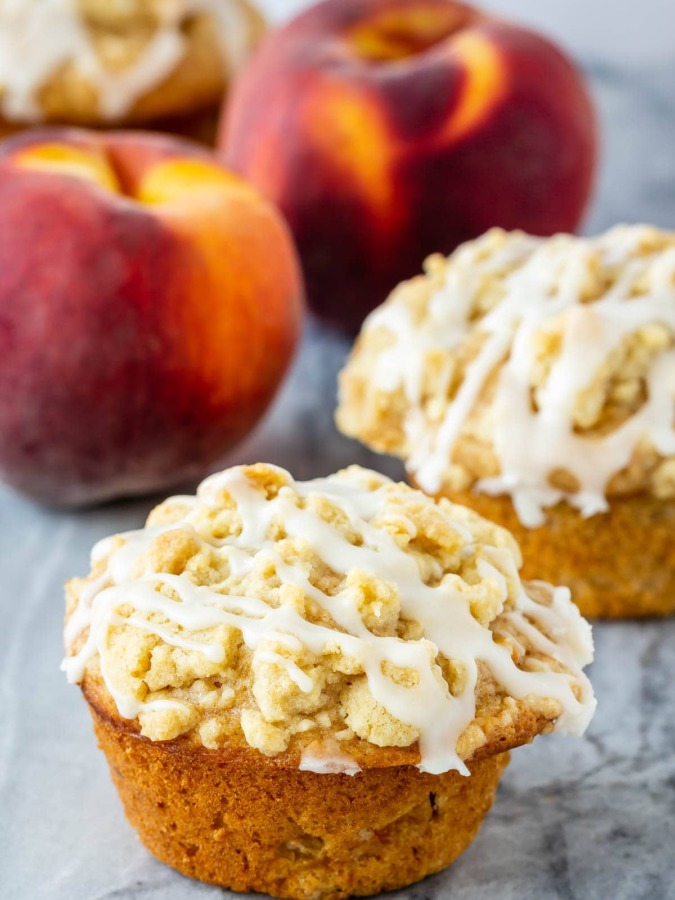 Peach muffins with a crumb topping and a vanilla glaze