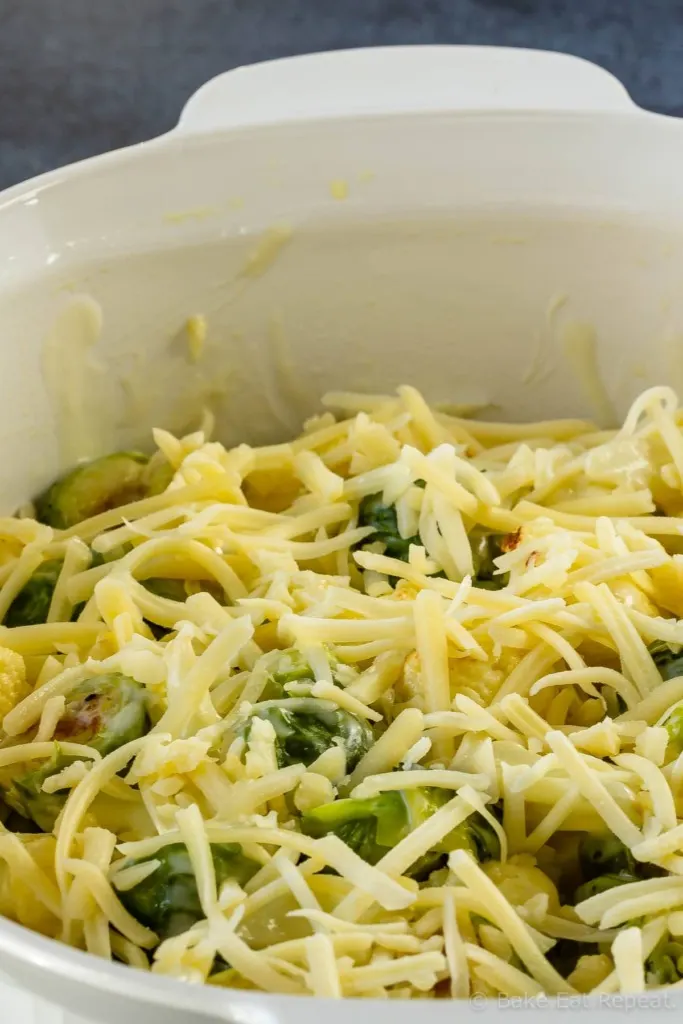 Cheese sprinkled over roasted brussel sprouts and cauliflower that are coated in a homemade cheese sauce