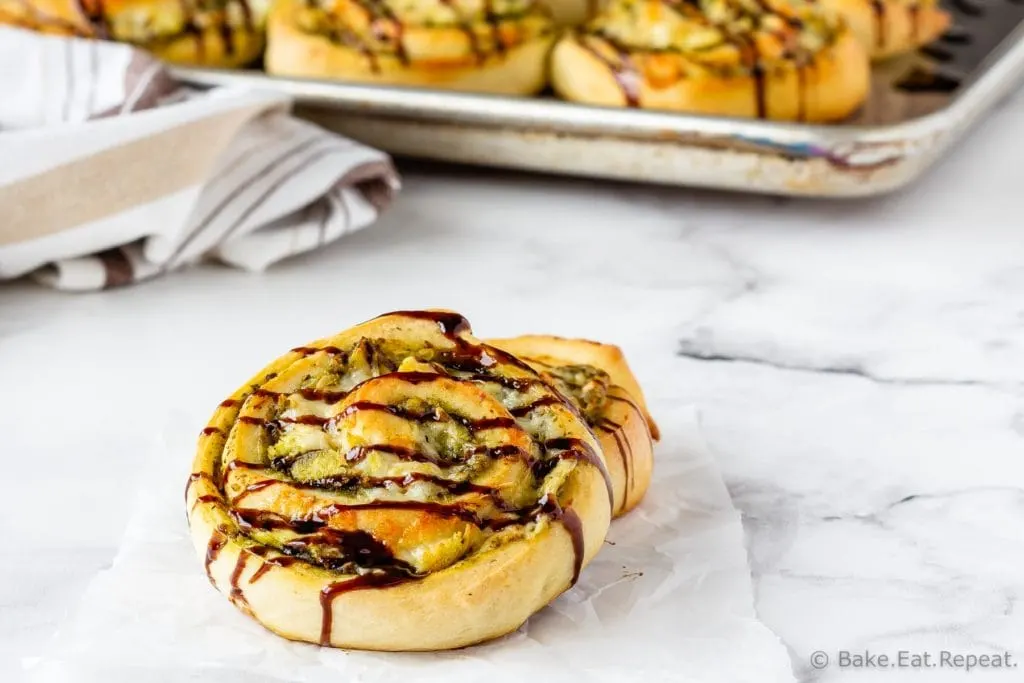 Easy to make pesto chicken pizza rolls drizzled with balsamic glaze.