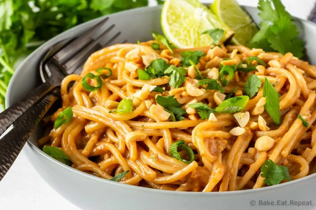 Homemade peanut pasta sauce on noodles with lime, green onions, and cilantro