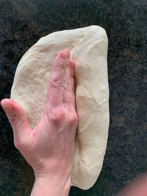 Shaping bread dough into a loaf, sealing the seam.