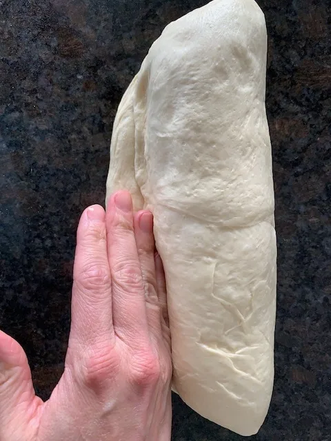 Shaping bread dough into a loaf, sealing the seam.
