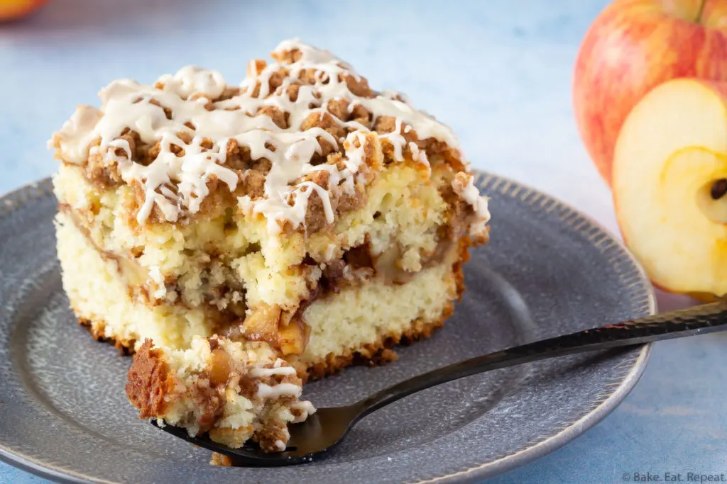 Easy cake filled with cinnamon apples and topped with a crumb topping and salted caramel glaze on a plate.