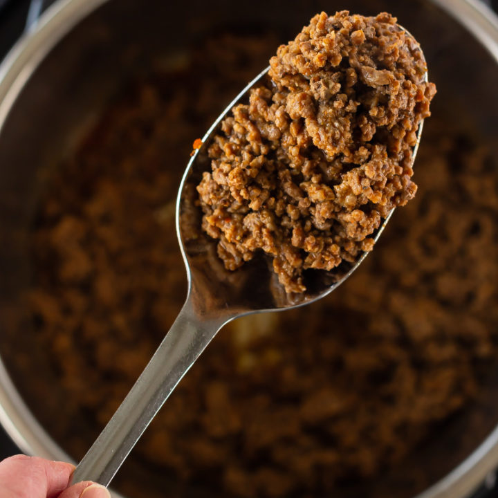A spoonful of cooked taco meat held above the Instant Pot where it was cooked from frozen ground beef.