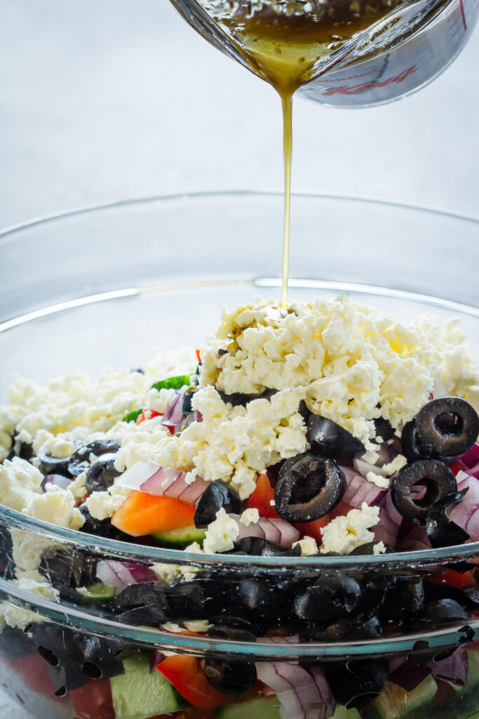 dressing being poured onto Greek quinoa salad